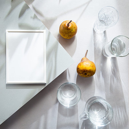 Mock up white photo frame top view. Summer still life scene with romantic shadows. Glasses with...