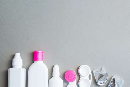 Contact lenses and accessories flat lay on a gray background. Composition with solution bottles and lens containers with copy spaceの写真素材