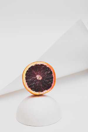 Creative still life with red orange fruits and white geometric shapes, spheres. Modern minimal...