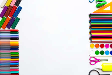 Bright still life scene of stationery on a white background. Colored pencils, felt-tip pens, plasticine and paints, flat lay with a place for text.の写真素材