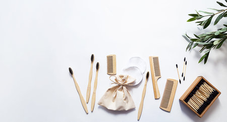 Organic bamboo toothbrushes, ear sticks and reusable cotton sponges on a white background with...