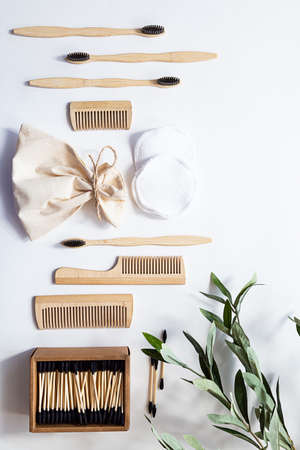 Organic bamboo toothbrushes, ear sticks and reusable cotton sponges on a white background with interesting olive branch shadows. Zero waste essential bathroom products in a sustainable lifestyle.の写真素材