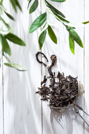 Dry blooming Sally in a tea strainer close-up. Alternative herbal medicine. Healthy lifestyle concept. Composition with organic, natural, fermented willow-herb tea on a light wooden table.の写真素材