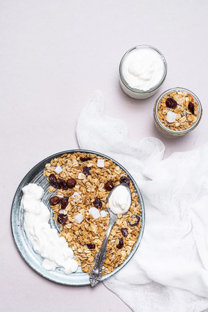 Granola with chia seeds, coconut, dry berries and yogurt in bowls on gray background, copy space....