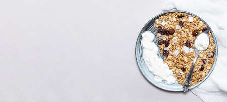 Granola with chia seeds, coconut, dry berries and yogurt in bowls on gray background, copy space. Concept of healthy breakfast menuの写真素材