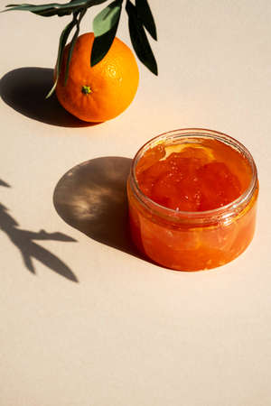 Jar of organic skin care mandarin gel. Package of cosmetic product body cream in sunlight with shadows of olive branches. SPA treatment or beauty industry concept.の写真素材