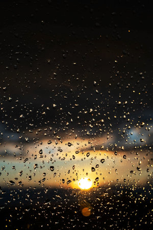 Window glass after rain with water drops. Background of stormy sunset sky.