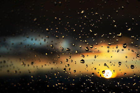 Window glass after rain with water drops. Background of stormy sunset sky.