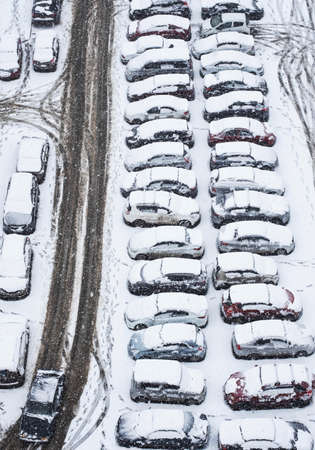 First snow in the parking lot, view from above. Many cars covering with snow.の写真素材