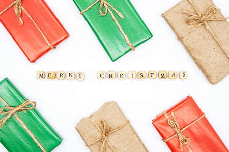 Merry Christmas - text made from wooden cubes, gift boxes on a white, flat lay. Winter holidays greeting card, Invitation or leaflet.の写真素材