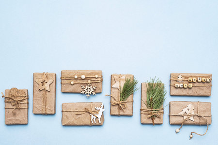 Christmas presents wrapped brown paper, decorated wooden toy, flat lay on blue background. Winter holiday composition with place for text.の写真素材