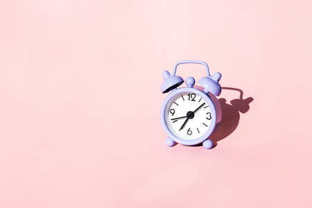 Violet vintage alarm clock on pastel pink background. Concept of time, morning, time to work or deadline.の写真素材