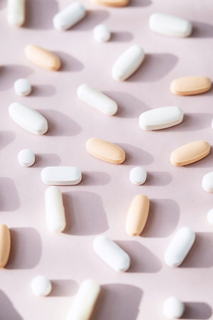 Different pills, vitamin capsules on pastel pink background. Dietary supplement supports for health.の写真素材