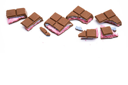 Broken pieces chocolate bar with pink blue filling on white. Crumbled chocolate bar of various size...