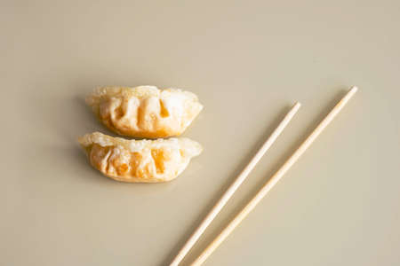 Fried gyoza dumpling and bamboo chopsticks, minimal style. Asian food.の写真素材