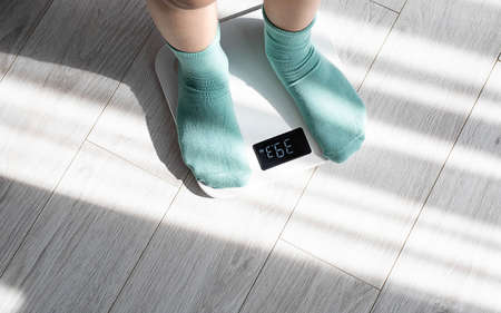 Boy legs stepping on floor scales at home. Weight control concept.の写真素材