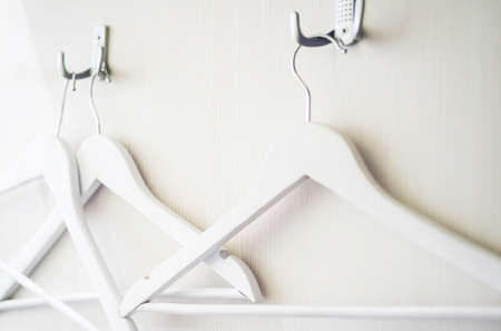 Empty clothes hanger hook, close up. Some wooden white hangers on white wooden background, selective focus.の写真素材