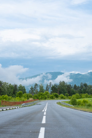 Empty road. Speedway without cars in mountains amid pine forests. Adventure or road trip background.