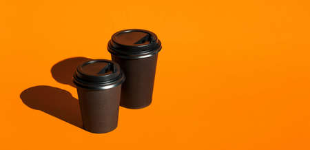 Paper coffee cups against orange background.の写真素材