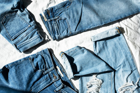 Denim collection. Jeans on white textile background, top view. Casual clothing. Sale concept.