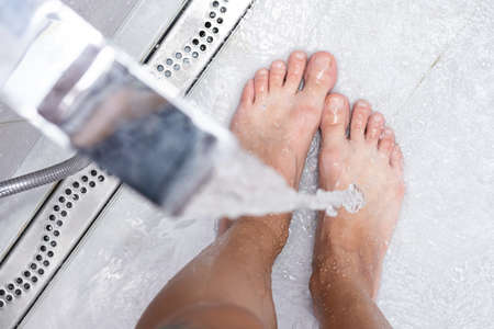 Woman washing feet, close up. Female stands under shower water.の写真素材