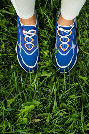 Woman's legs in blue sneakers outdoor, close up. Modern sport fashion concept.の写真素材
