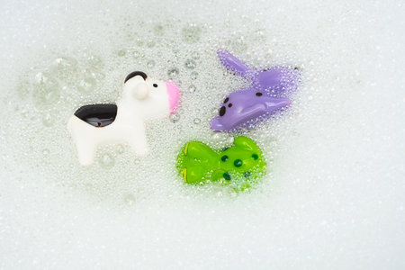Rubber toys in bath bubbles. Colourful animal toys in soapy foam.