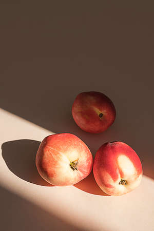 Peaches in sunlight. Minimalism, trendy still life with shadow.の写真素材