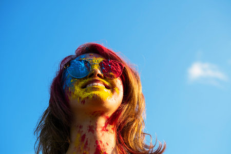 Woman covered in holi powder against blue sky. Holi colors festival.