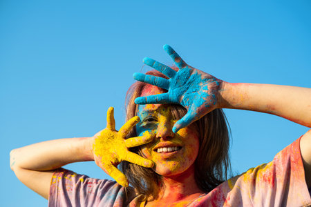 Woman covered in holi powder against blue sky. Holi colors festival.の写真素材