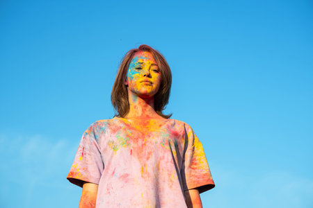 Woman covered in holi powder against blue sky. Holi colors festival.