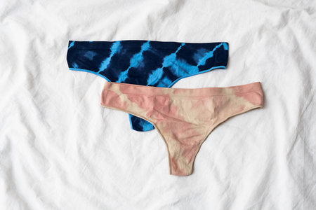 Two female panties on white bedding. Flat lay with daily underwear.