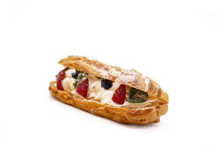 Traditional french dessert opened eclair with buttercream, fresh strawberries, icing sugar and mint on white.の写真素材