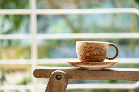 Handcraft bamboo cup of coffee or tea in sunlight. Summer morning on balcony.の写真素材