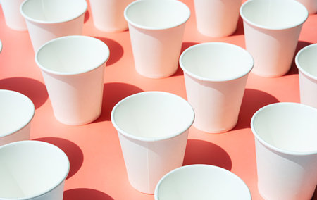Several disposable white paper cups. Mock up to go coffee cups with shadows on pink.の写真素材
