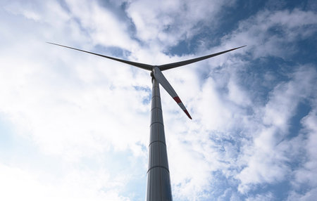 Wind generator turbine against blue cloudy sky.