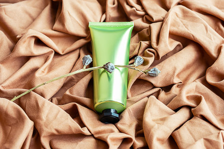 Cosmetic tube on textile background. Skin care beauty product layout.