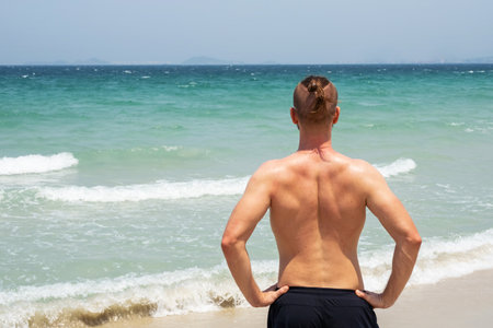 Rear view shirtless man ready to swim. Male enjoying summer day at sea shore.の写真素材