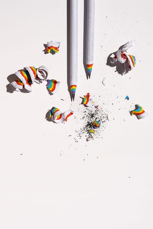 Lead pencil with colorful shavings on white.