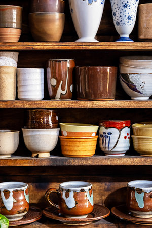 Various pottery ceramic displayed on wooden shelves at store.の写真素材
