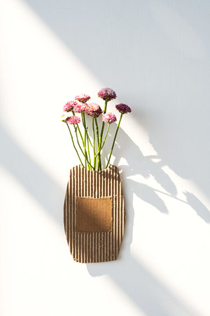Small bouquet of flowers in cardboard vase.