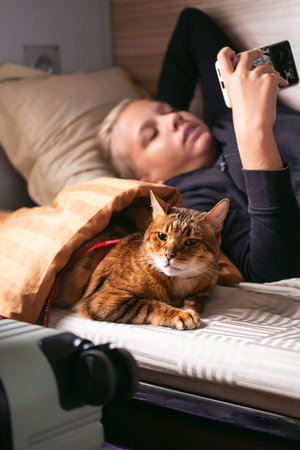 Teenager uses smartphone while travelling with his cat on a train.の写真素材