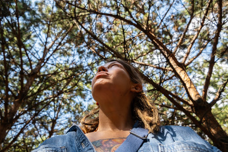 Woman looking up through the trees in the summery forest.の写真素材