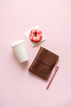 Disposable coffee cup, donut and brown notebook. Time break and productivity concept.