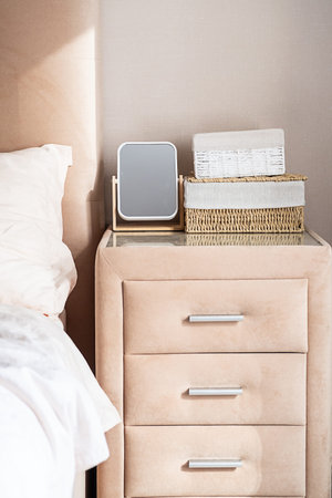 Minimalist bedroom nightstand with mirror and storage baskets.の写真素材