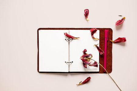 Open notebook with dried flower petals and pen. Creativity, writing or nostalgia concepts.