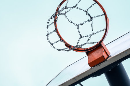 Basketball hoop with metal chain net against clear sky.の写真素材