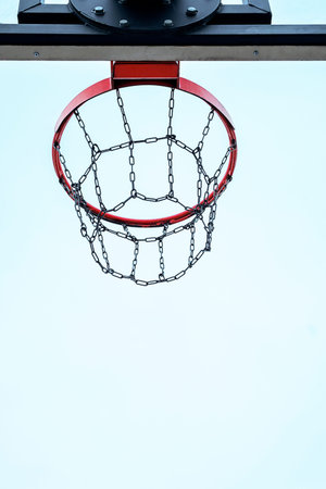 Basketball hoop with metal chain net against clear sky.の写真素材