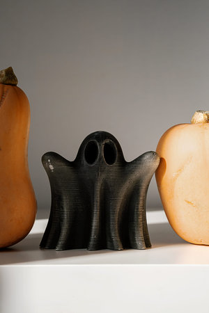 Decorative ghost figure between pumpkins.