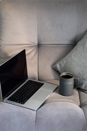 Cozy workspace showing laptop and mug on soft couch.